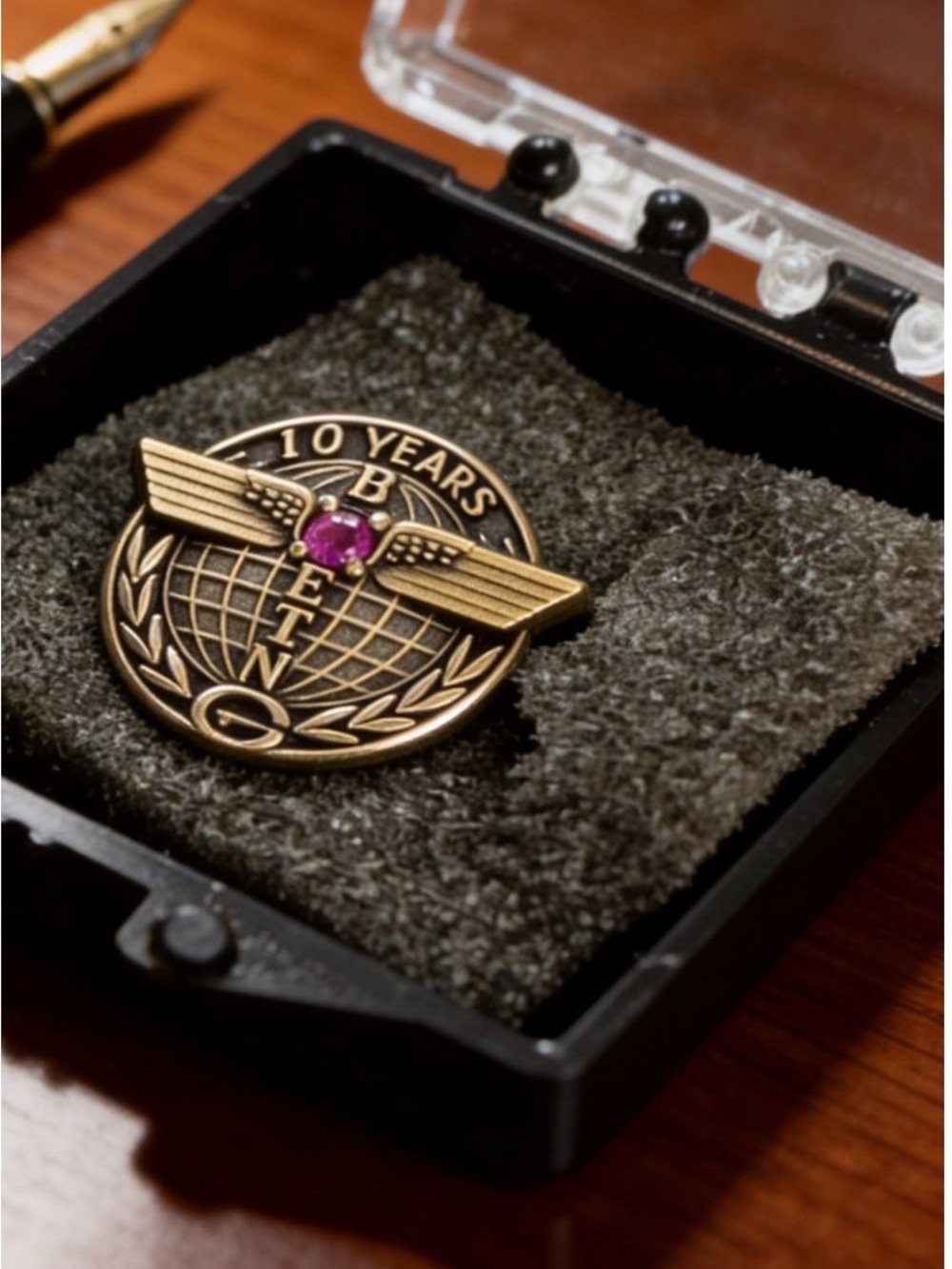 Gold-Tone 'BEING' 10 Years Commemorative Brooch with Pink Gem